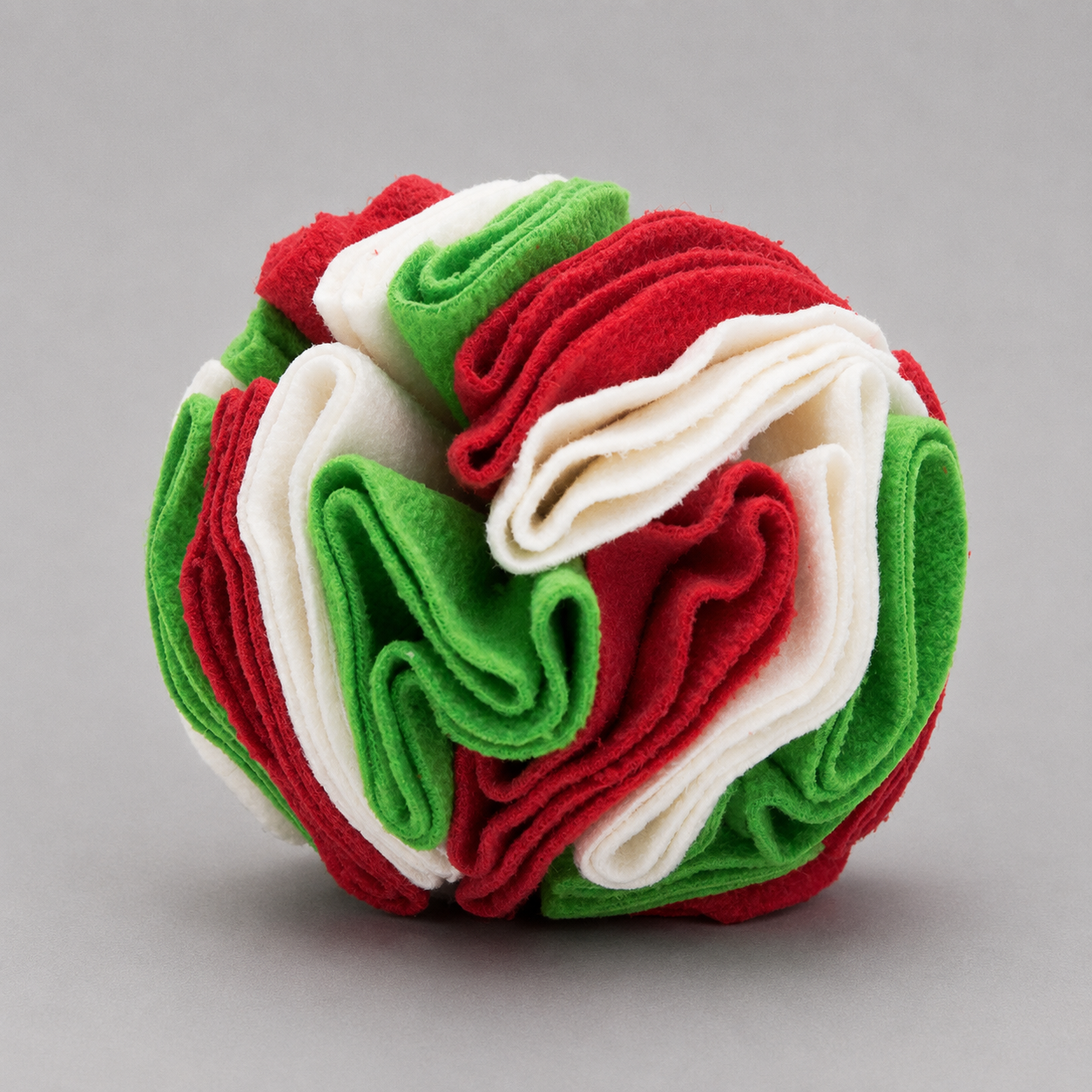 Colorful ball made of folded fabric in red, green, and white on a grey background