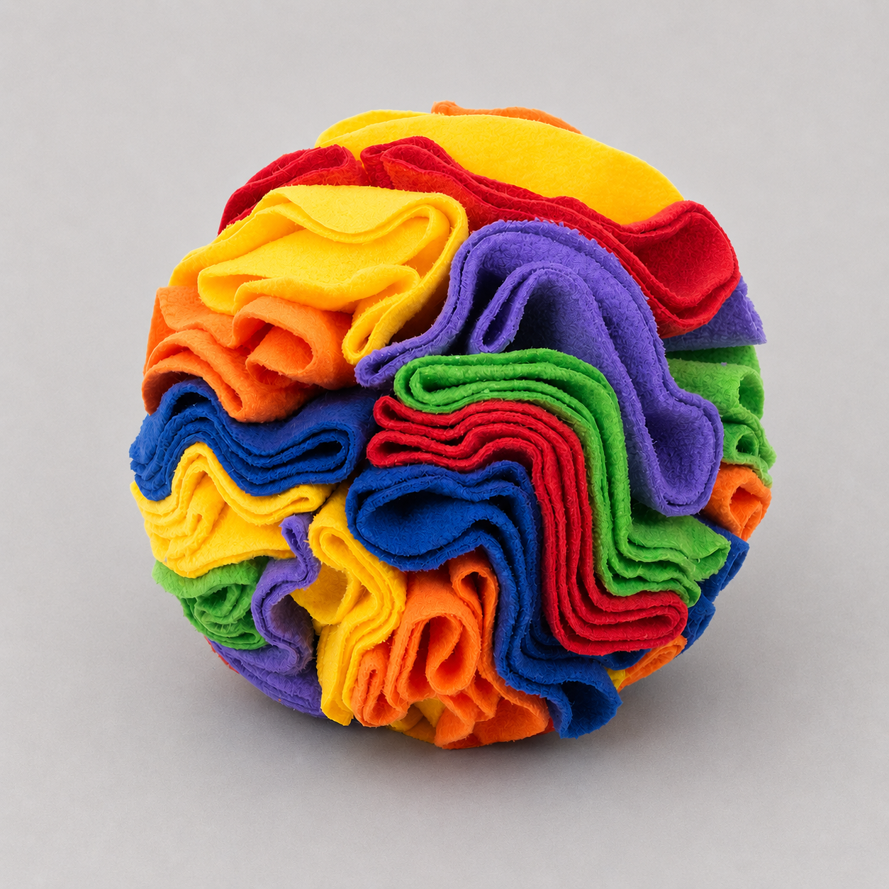 Ball of colorful fabric strips in a rainbow pattern on a grey background