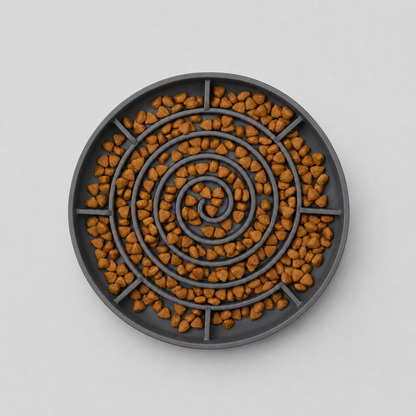 Aerial image of a grey spiral slow feeding dog bowl filled with brown kibble on a light grey background